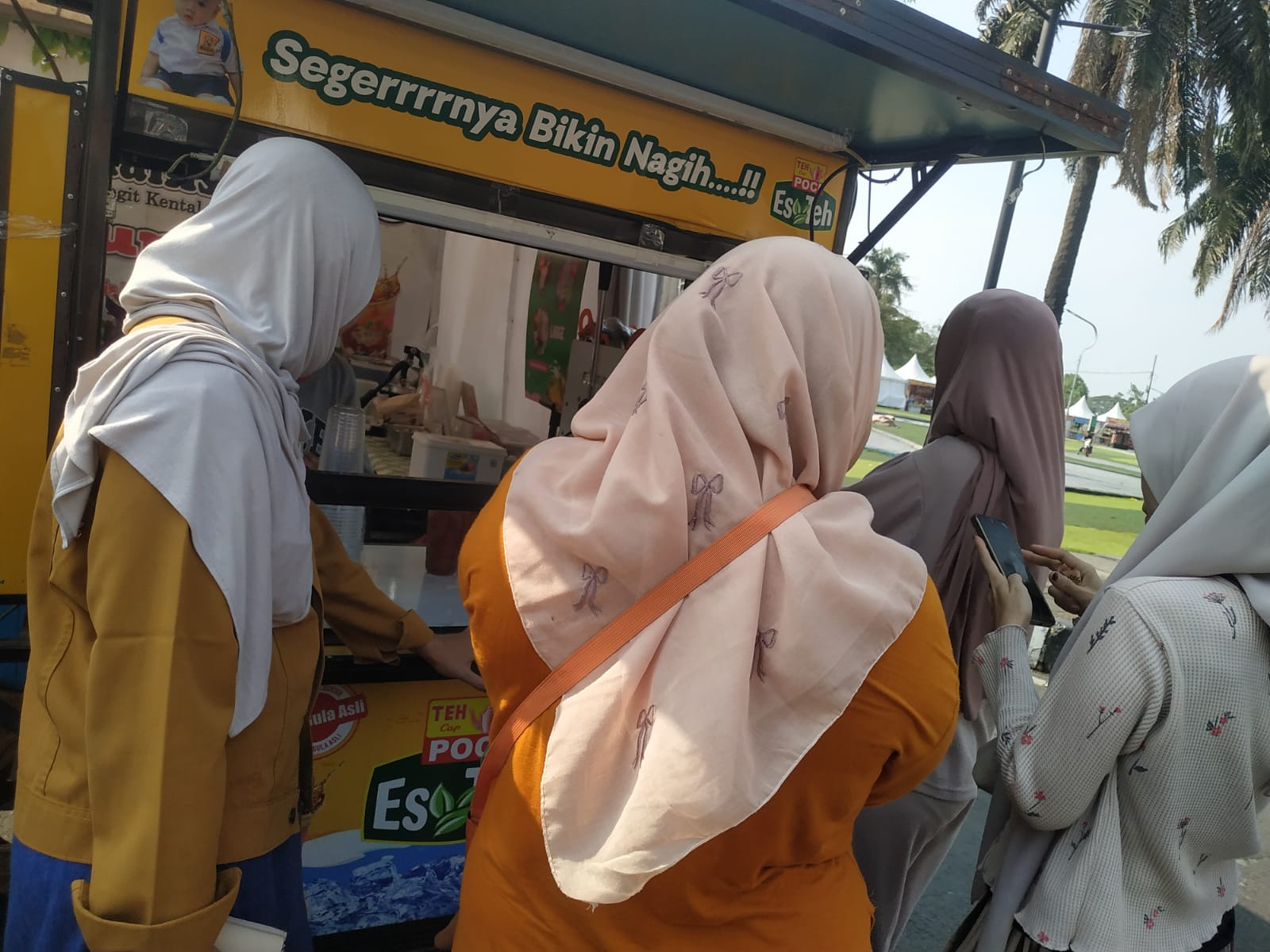 Pembeli remaja perempuan berhijab antre membeli Es Teh Poci di gerobak kuning Della di Taman Elektrik Masjid Raya Al-Azhom Tangerang