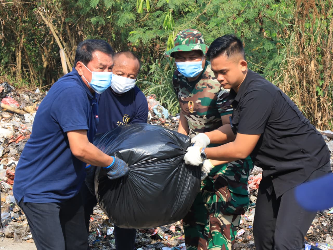 Bupati Tangerang Moch Maesyal Rasyid memakai kaos biru dan masker bersama TNI mengangkat kantong sampah hitam berukuran besar dalam kegiatan Jumat Bersih di Desa Tobat Balaraja pada 19 Juni 2026
