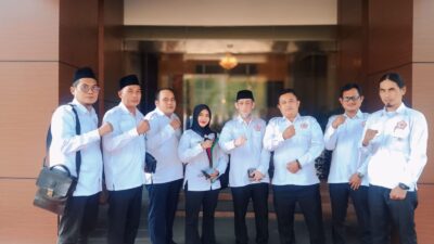 Delapan pengurus DPW GMPK Banten dan DPD GMPK Kabupaten Tangerang memakai seragam putih berlogo GMPK berpose mengepalkan tangan di depan Gedung Kejari Kabupaten Tangerang sebelum audiensi pada 19 Juni 2026