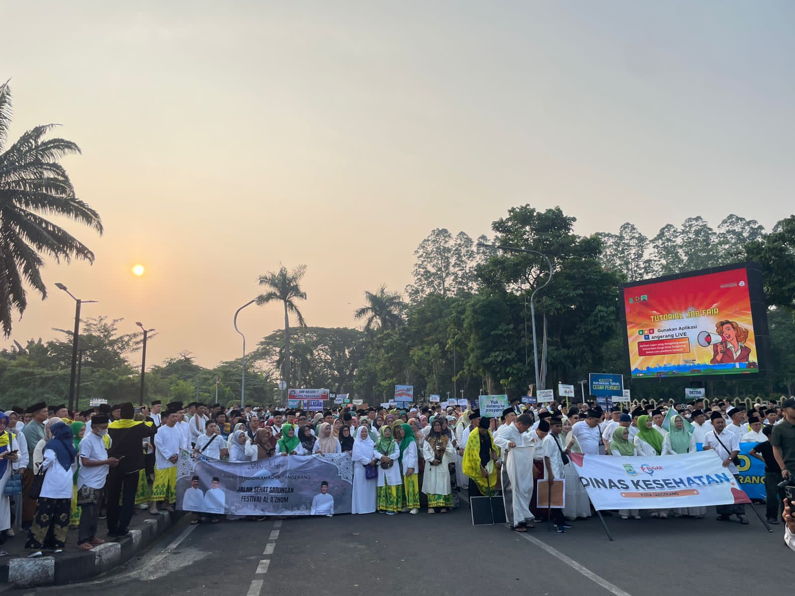 Peserta Jalan Sehat Sarungan dari Dinas Kesehatan Kota Tangerang membawa spanduk besar saat berjalan pagi di Festival Al Azhom 2026