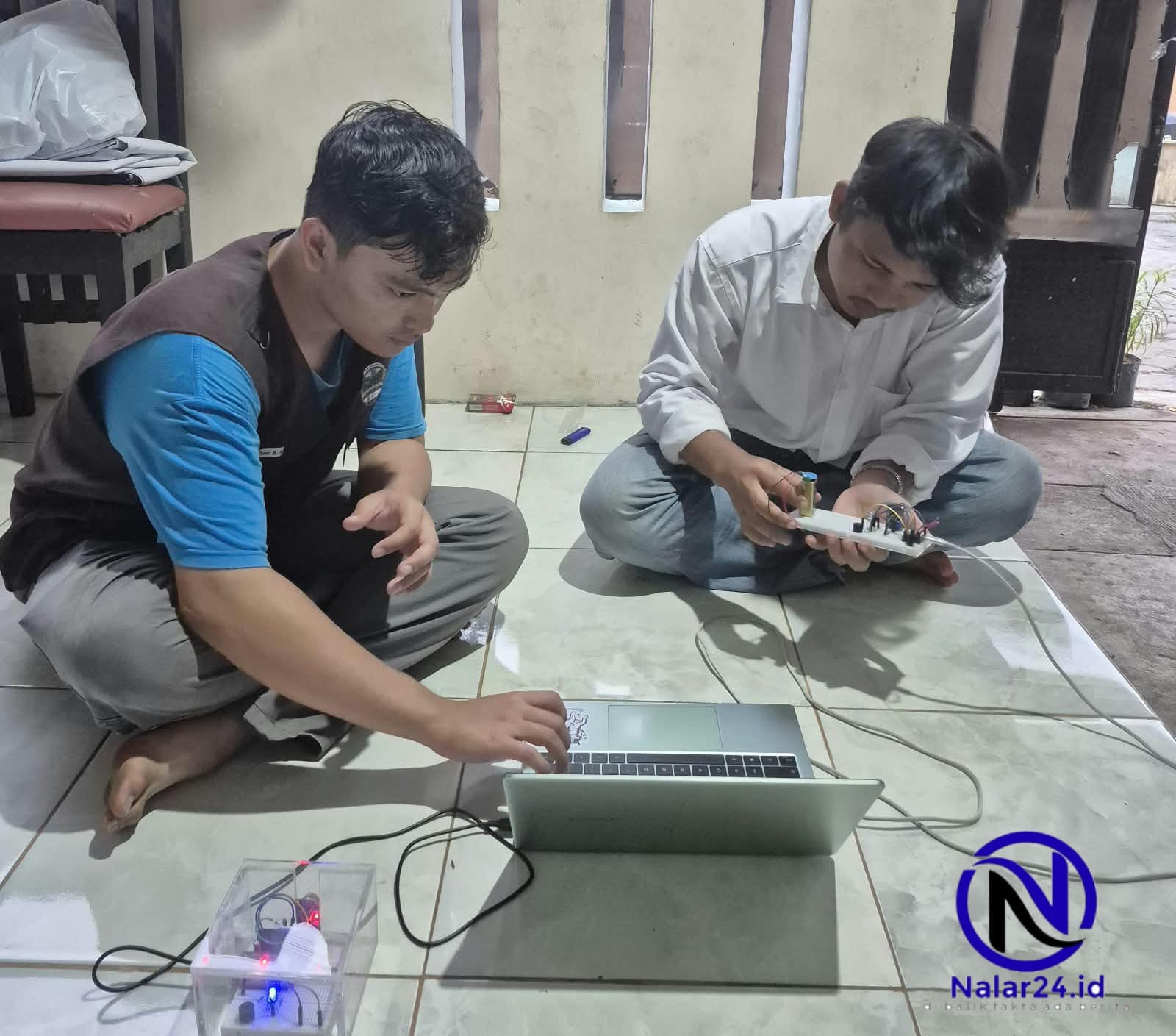 Mahasiswa Uniba duduk lesehan sambil merakit alat deteksi gas dan membuka laptop