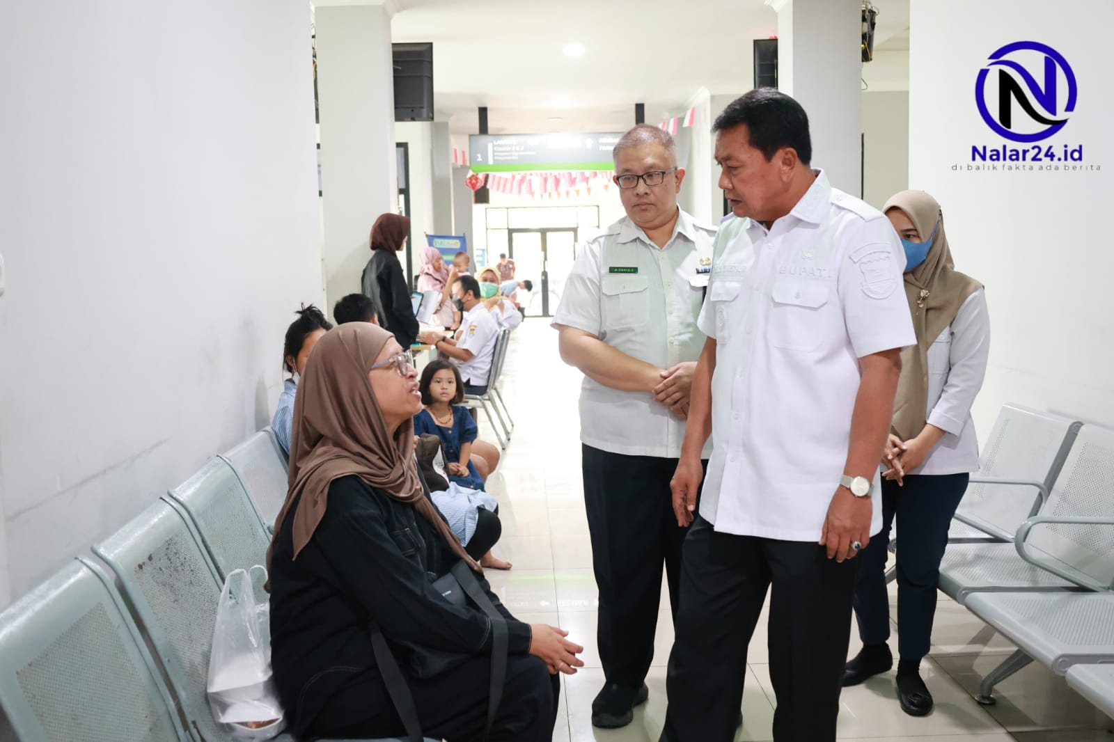 Bupati Maesyal berdiri berbincang dengan ibu-ibu pasien di kursi tunggu Puskesmas