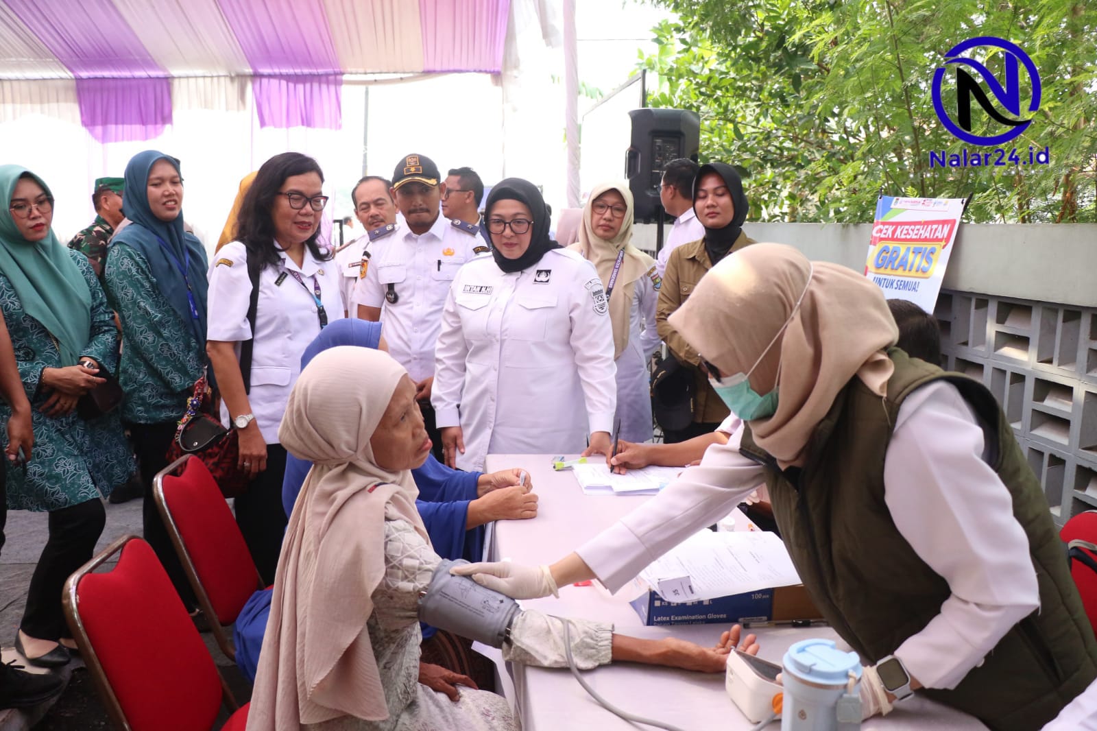 Wabup Intan dan jajaran melihat petugas kesehatan memeriksa tensi warga di kegiatan Balita Kita Sehat