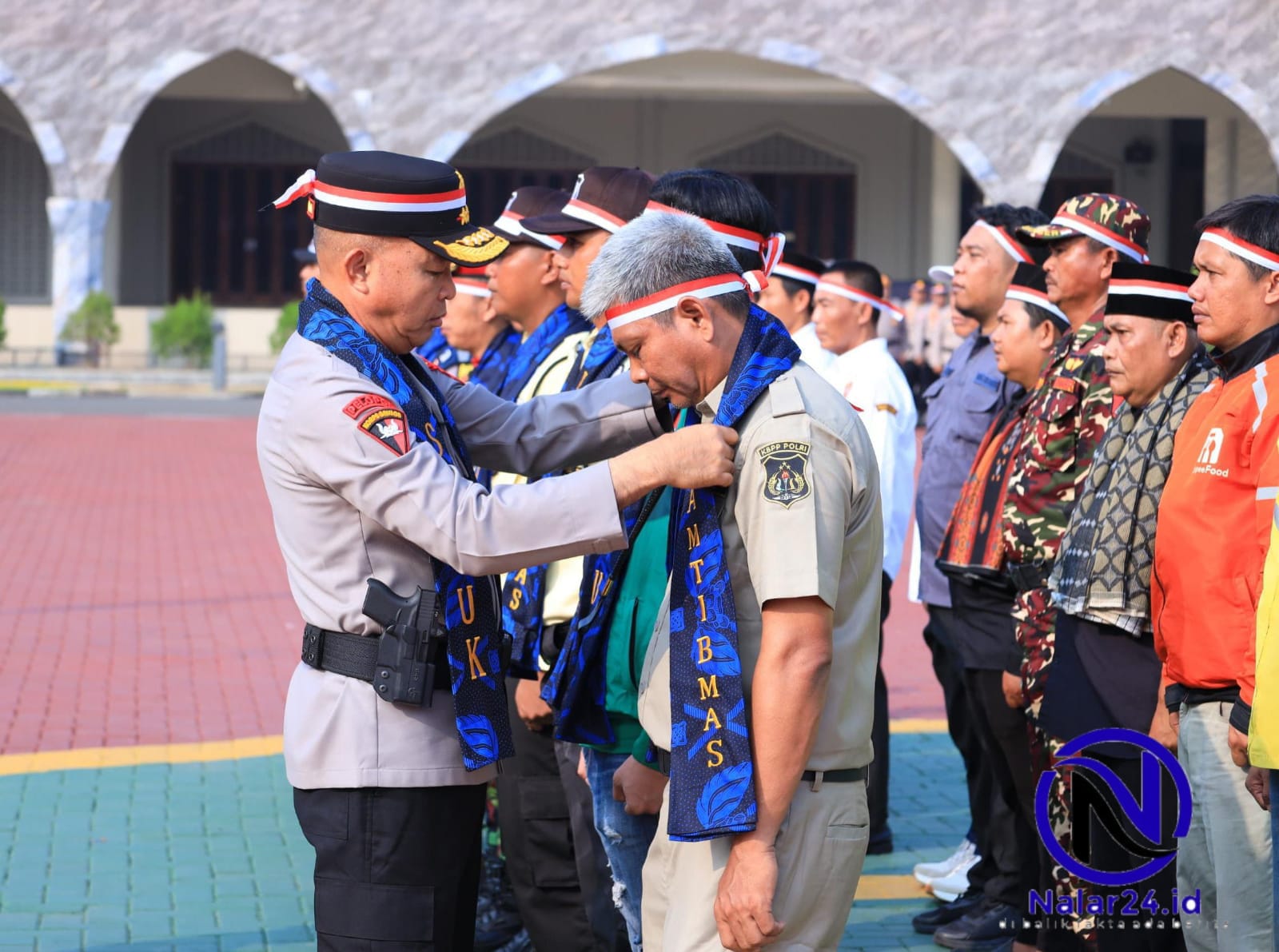 Petugas polisi menyematkan selempang kepada warga sipil di lapangan apel