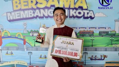 Pria tersenyum memegang trofi dan sertifikat penghargaan dari Pemkot Tangerang