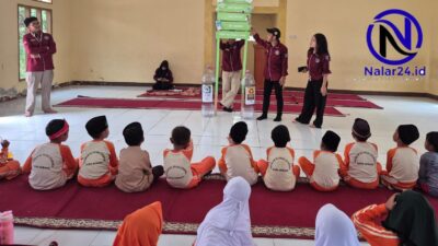 Mahasiswa KKM menjelaskan tentang masa urai sampah kepada siswa SD duduk di karpet