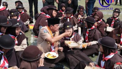 Bupati Tangerang duduk lesehan di rumput menyuapi makanan kepada anggota Pramuka putri