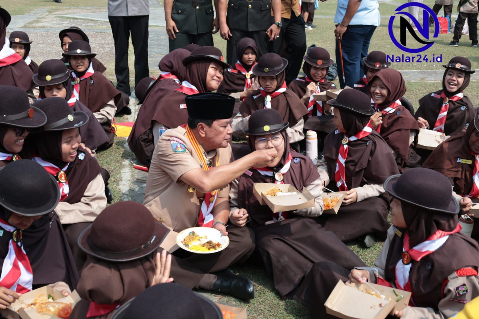 Bupati Tangerang duduk lesehan di rumput menyuapi makanan kepada anggota Pramuka putri