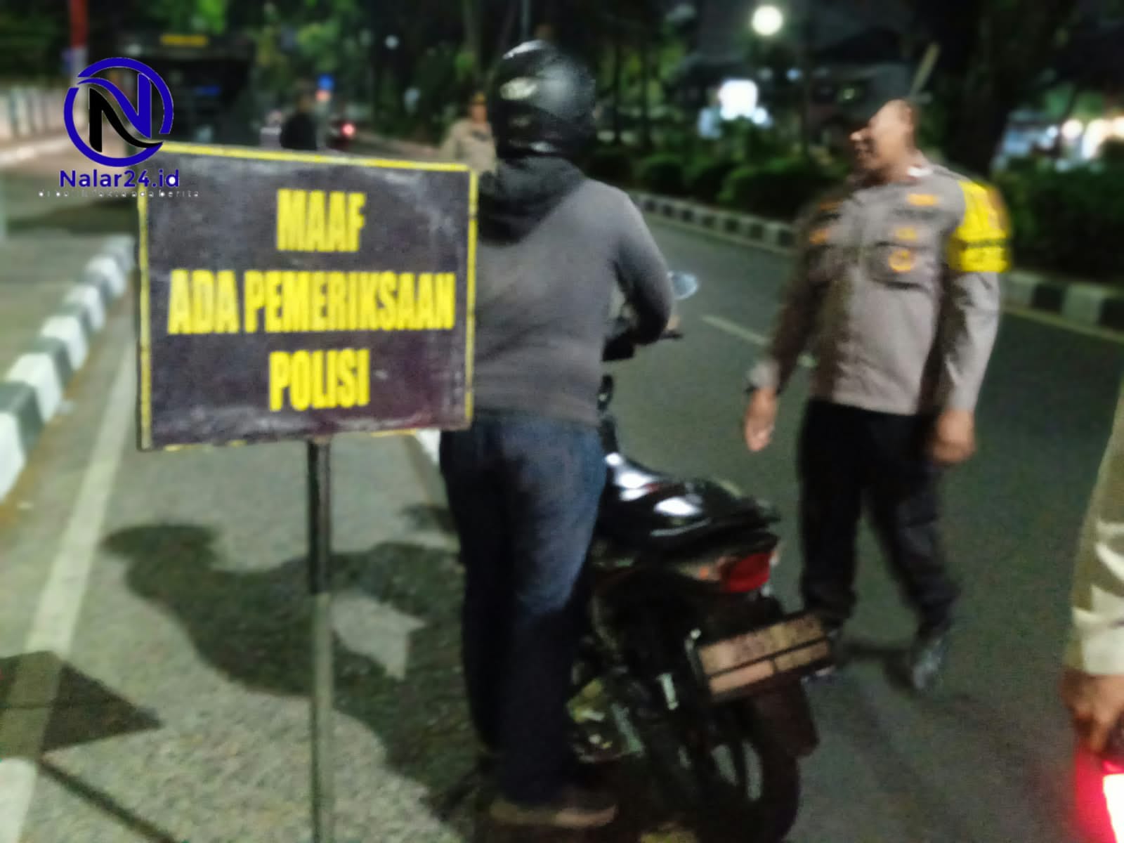 Suasana ramah polisi berbincang dengan pengendara motor di pos pemeriksaan patroli malam hari