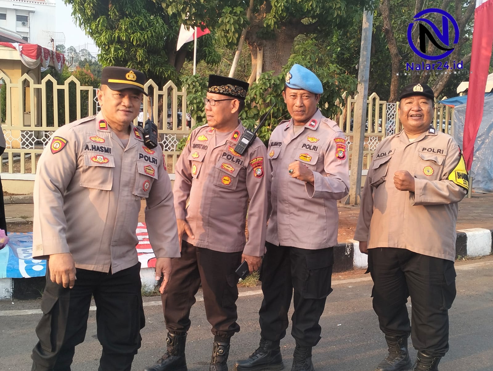 Empat orang anggota polisi memakai seragam coklat berdiri di pinggir jalan sambil berbincang