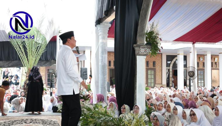 Seorang pria memakai baju putih dan peci hitam berdiri di atas panggung berbicara di depan ratusan jamaah perempuan yang memakai hijab warna-warni