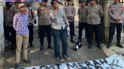 Koordinator BMAP berorasi di depan kantor dengan spanduk bertuliskan rapot merah DPMPTSP