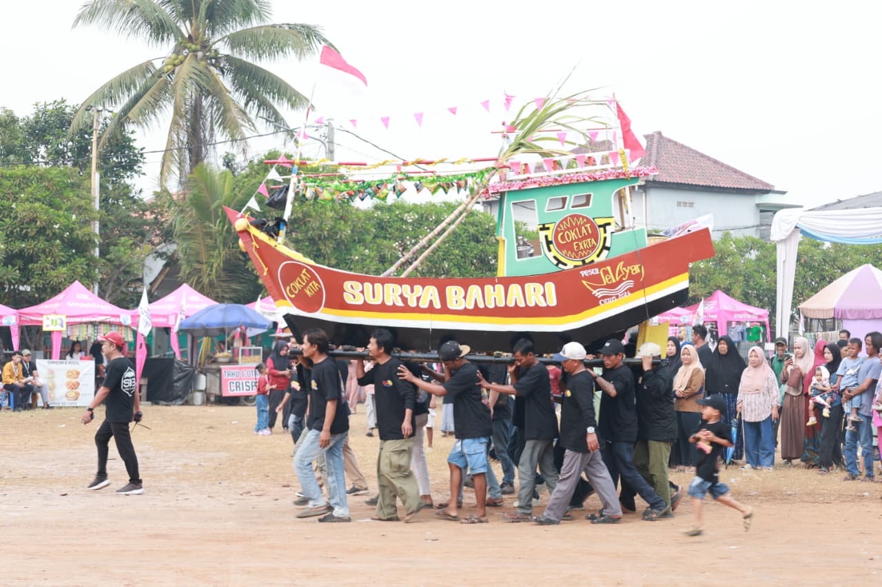 Warga Desa Surya Bahari mengarak miniatur kapal nelayan bertuliskan Surya Bahari saat Pesta Nelayan 2026 di Pakuhaji Kabupaten Tangerang