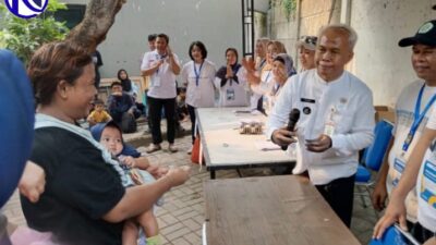 Lurah Babakan Teguh berbincang dengan warga penerima bansos beras yang membawa balita di Kantor Kelurahan Babakan,